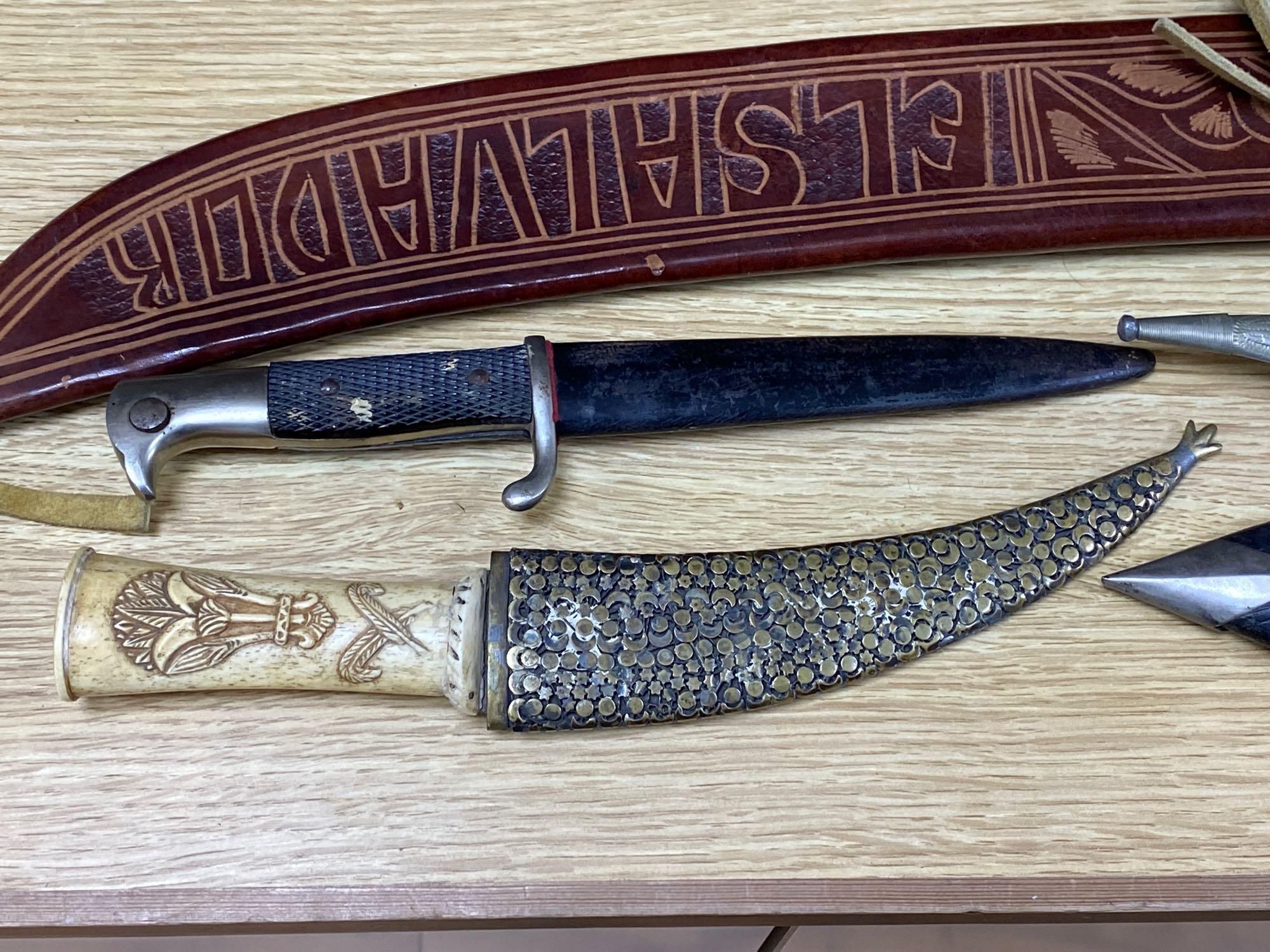 Five various weapons including a Kukri, a carved bone handled dagger with brass sun, moon and stars sheath and an El Salvador machete